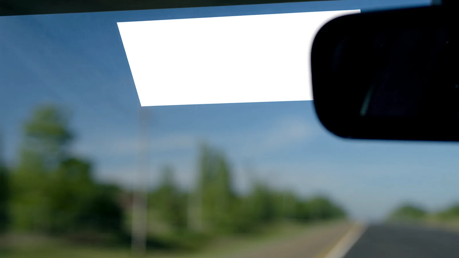An electronic toll tag mounted on the inside of a car windshield beside the rear-view mirror