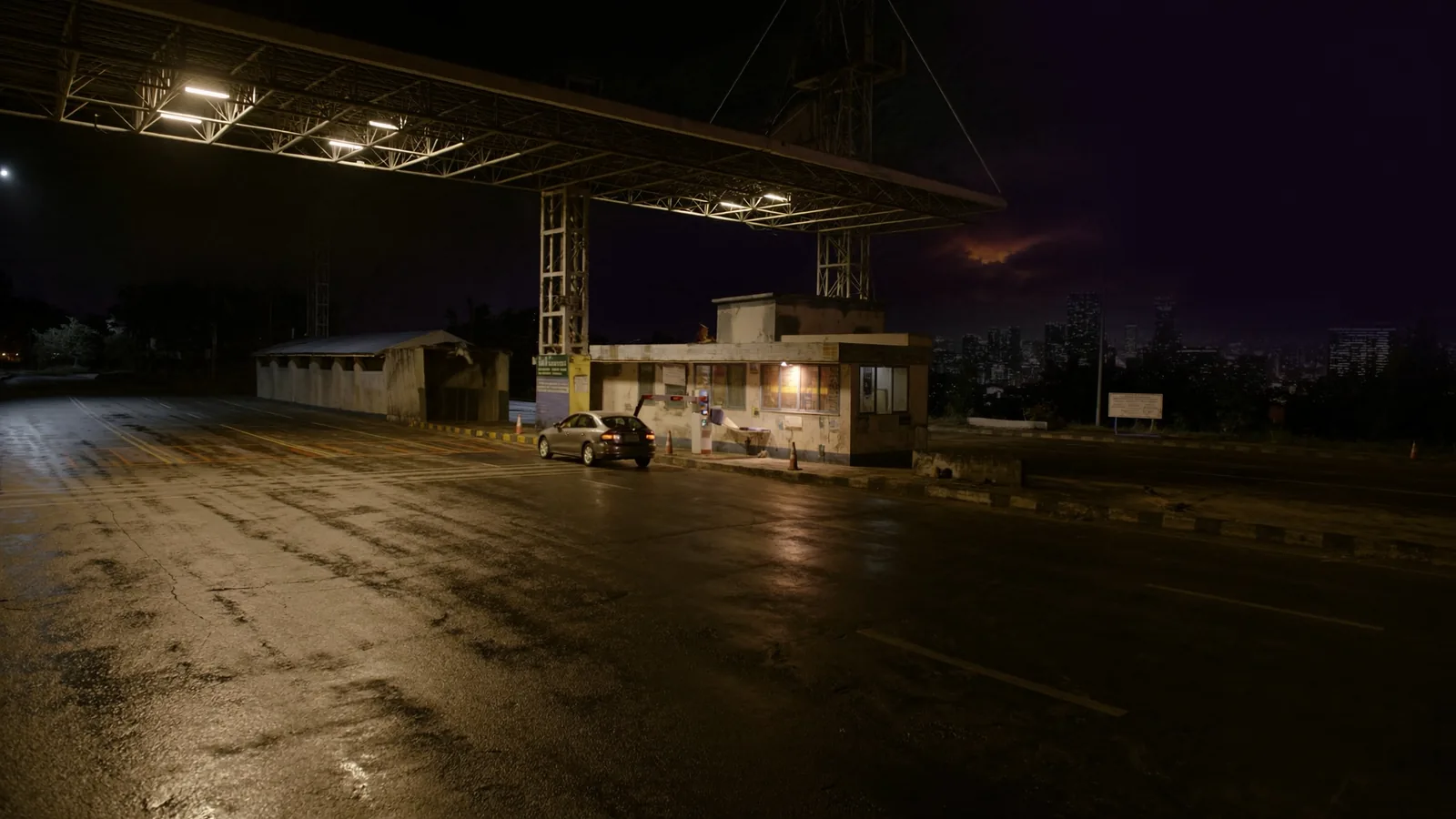 A car at an electronic toll lane at night as the barrier arm lifts on a Philippine expressway